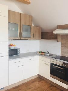 a kitchen with white appliances and wooden cabinets at Ferienwohnung Steirerbusserl in Kirchdorf