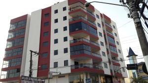 un grand bâtiment rouge et blanc dans l'établissement Apartamentos na cobertura - Edifício London, à Piratuba