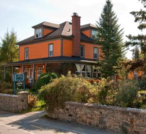 a large orange house with a tree in front of it at À Tout Venant B&B in Magog-Orford