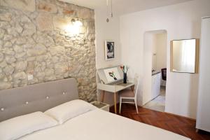 a bedroom with a stone wall with a bed and a desk at Pinta Apartments in Lumbarda