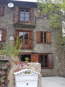 ein Steingebäude mit Holzfenstern und einem Balkon in der Unterkunft Casa Joanet in Unarre
