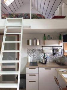 a kitchen with white cabinets and a loft bed at Le Gîte "Le Grand Chêne" in Le Cloître-Saint-Thégonnec