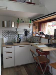 a kitchen with white cabinets and a wooden table at Le Gîte "Le Grand Chêne" in Le Cloître-Saint-Thégonnec +4 photos