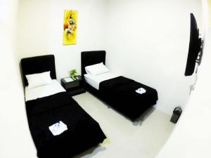 a small room with two beds and a tv at login homestay in Madiun