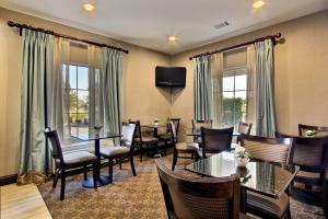 Magnolia Inn and Suites Pooler في سافانا: مطعم به طاولات وكراسي وتلفزيون