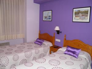 2 camas en un dormitorio con paredes moradas en Pensión El Camarote, en Cudillero
