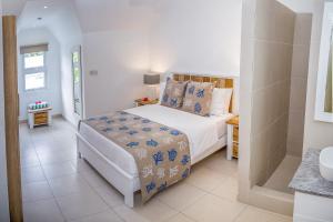 una camera da letto bianca con un letto e un bagno di Villas Coco Beach Praslin ad Anse Kerlan