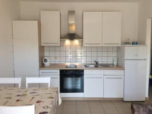 cocina con armarios blancos, fregadero y mesa en Apartments Parać, en Petrčane