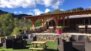 a patio with a table and a stone wall at Camping Calme et Nature in Castellane