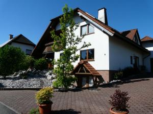 uma casa branca com uma árvore em frente em Ferienwohnung Udo und Stefani Laux em Berg