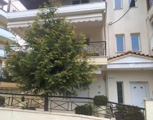 un árbol frente a un edificio con una valla en Litochoro Apartments, en Litóchoron