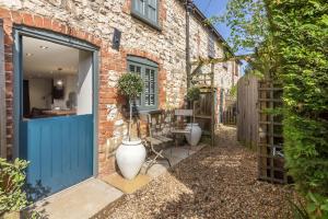 a brick house with a blue door and a garden at No33 THORNHAM BOUTIQUE COTTAGE 2 in Thornham