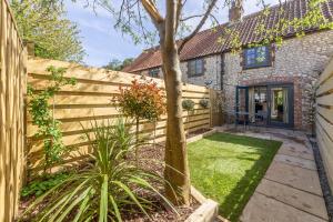 a backyard with a fence and a tree at No33 THORNHAM BOUTIQUE COTTAGE 2 in Thornham
