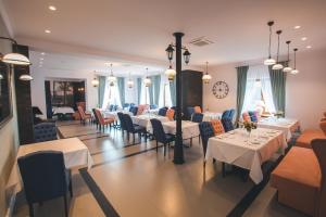 a dining room with white tables and chairs and a clock at Novopolska - Hotel i Restauracja in Kościan