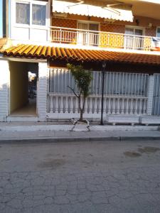 a building with a white fence and a tree in front of it at Family-Elia in Paralia Dionysiou