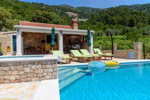 a swimming pool with a patio and a house at Villa Lucija Bol in Bol
