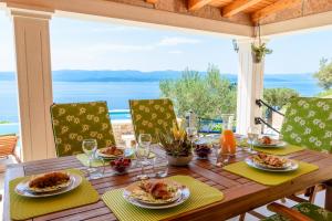 a wooden table with plates of food and a view of the ocean at Villa Lucija Bol in Bol
