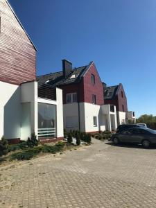 a row of houses with a car parked in a parking lot at Baltic Vip Apartamenty Letnie w Rewalu in Rewal