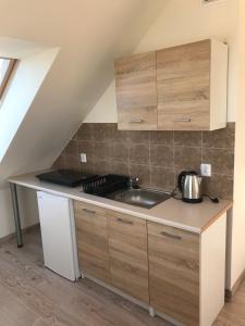 a kitchen with wooden cabinets and a sink at Baltic Vip Apartamenty Letnie w Rewalu in Rewal