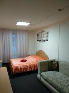チュメニにあるHotel Four Roomsのベッドルーム1室(ベッド1台、ソファ、椅子付)