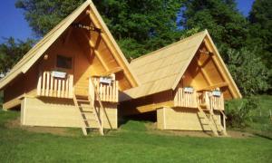 uma grande casa de jogos de madeira com um telhado inclinado em farmglamping Planika - Encijan em Hraše