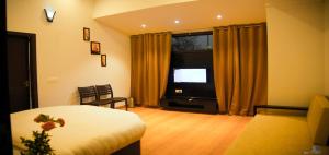 a bedroom with a bed and a television in a room at La Bellevue (Club & Resort) in Rāmnagar
