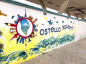 een muur met een muurschildering van de oceaan en de woorden osteria soina bij Ostello Salento in Alezio