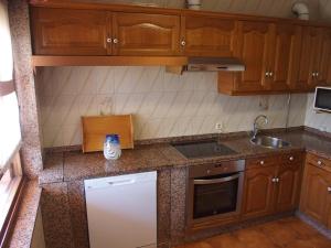 a kitchen with wooden cabinets and a white refrigerator at Casa Grande de Borizu Playa in Celorio +10 photos