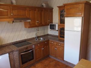 a kitchen with wooden cabinets and a white refrigerator at Casa Grande de Borizu Playa in Celorio