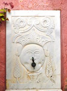 a statue of a face on the side of a wall at Rallou House Hydra in Hydra