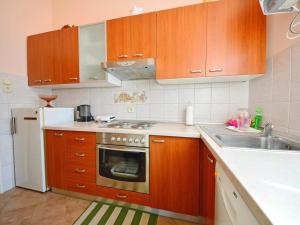 een keuken met houten kasten, een fornuis en een wastafel bij Villa Pelda Apartment, sea view, parking, pet friendly in Opatija