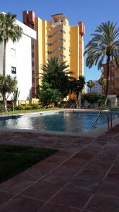 a swimming pool with palm trees and buildings at Apartamento Carihuela Beach & Sun in Torremolinos