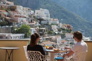 two people sitting at a table on a balcony with a view at Hotel Posa Posa in Positano