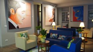 a waiting room with blue couches and a painting at Hotel Lucerna in Castiglione della Pescaia