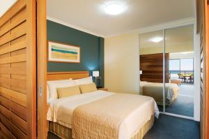 a hotel room with a bed and a sliding glass door at Oaks The Entrance Waterfront Suites in The Entrance