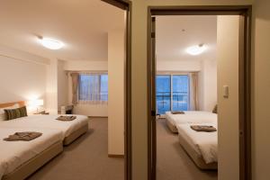 a hotel room with two beds and a mirror at One Niseko Resort Towers in Niseko