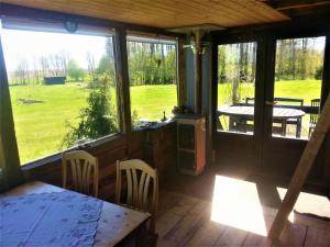 eine abgeschirmte Veranda mit einem Tisch, Stühlen und Fenstern in der Unterkunft Saulepa Cottage in Saulepa