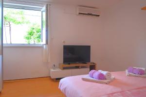 a white room with two beds and a flat screen tv at Studio apartman Mia in Stobreč