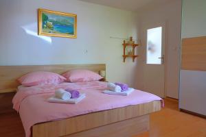 a bedroom with a bed with pink sheets and pink pillows at Studio apartman Mia in Stobreč