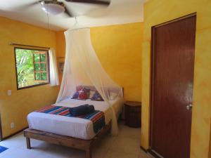 a bedroom with a bed with a mosquito net at Casa Abanico Tulum in Tulum