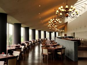 una sala da pranzo con tavoli, sedie e lampadari a braccio di Furano Resort Orika a Nakafurano