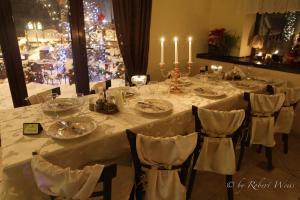 une grande table avec des nappes blanches et des bougies dans l'établissement Pensiunea Vlahia Inn, à Moieciu de Sus