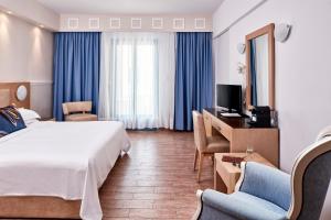 a hotel room with a bed and a desk and chairs at Lagos Mare Hotel in Agios Prokopios