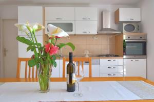 una mesa con una botella de vino y un jarrón con flores en Studio apartman Mia en Stobreč