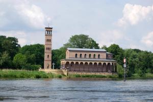 duży ceglany budynek z wieżą zegarową obok rzeki w obiekcie Ferienwohnung Babelsberg w Poczdamie