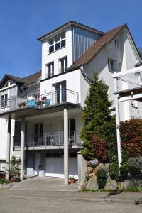 ein weißes Gebäude mit einem Balkon und einem Baum in der Unterkunft Ferienwohnung im Dettenbachtal in Waldkirch