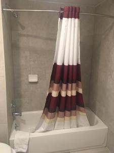 a bathroom with a shower curtain next to a bath tub at Caravan Motel in Niagara Falls