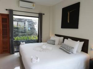 1 dormitorio con 1 cama blanca grande y ventana en Limelight Village, en Thong Nai Pan Yai