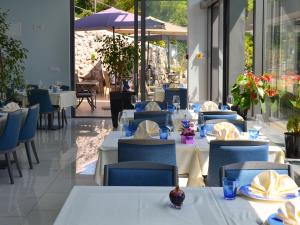un restaurante con mesas blancas y sillas azules en Boutique Hotel Mali Raj en Opatija