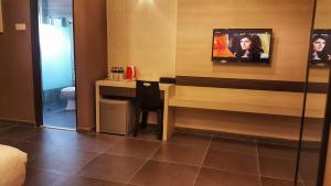 a hotel room with a desk and a tv on the wall at Kampar Boutique Hotel (Kampar Sentral) in Kampar